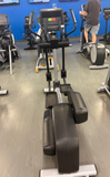 An athlete exercising on a Life Fitness Integrity Series INX elliptical cross-trainer inside a brightly lit commercial fitness center.