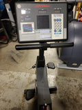 Detailed view of the contoured injection-molded seat on a Lifecycle 9100 exercise bike, showing the metal vertical adjustment post with 1/2-inch locking increments.