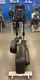 An athlete exercising on a Life Fitness Integrity Series INX elliptical cross-trainer inside a brightly lit commercial fitness center