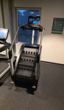 A commercial Life Fitness PowerMill climber positioned alongside other premium cardio equipment on a fitness center floor with high architectural clearance