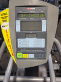  A physical therapy patient exercising on a charcoal gray SCIFIT SXT7000 total body elliptical, engaging both the synchronized moving handlebars and pedals for a low-impact workout.