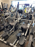 Three-quarter profile shot of a dark charcoal SCIFIT SXT7000 commercial total body elliptical standing on a white background, highlighting its low step-up base and articulating footbeds.